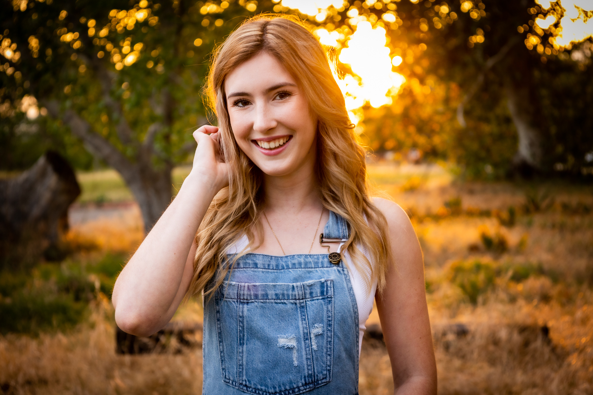 girl wearing overalls during golden hour during spring senior session in red bluff, ca