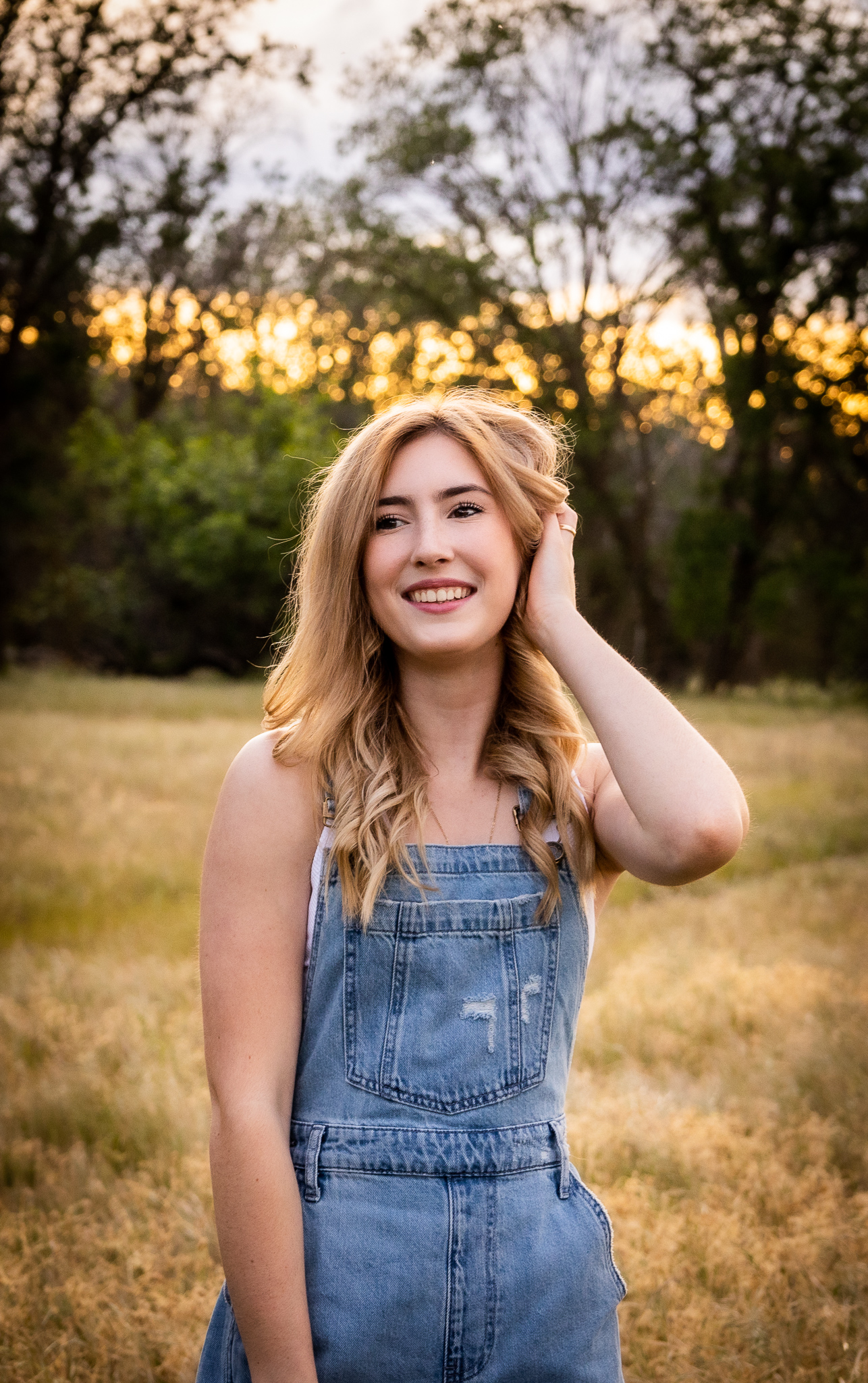 girl wearing overalls standing in red bluff ca field