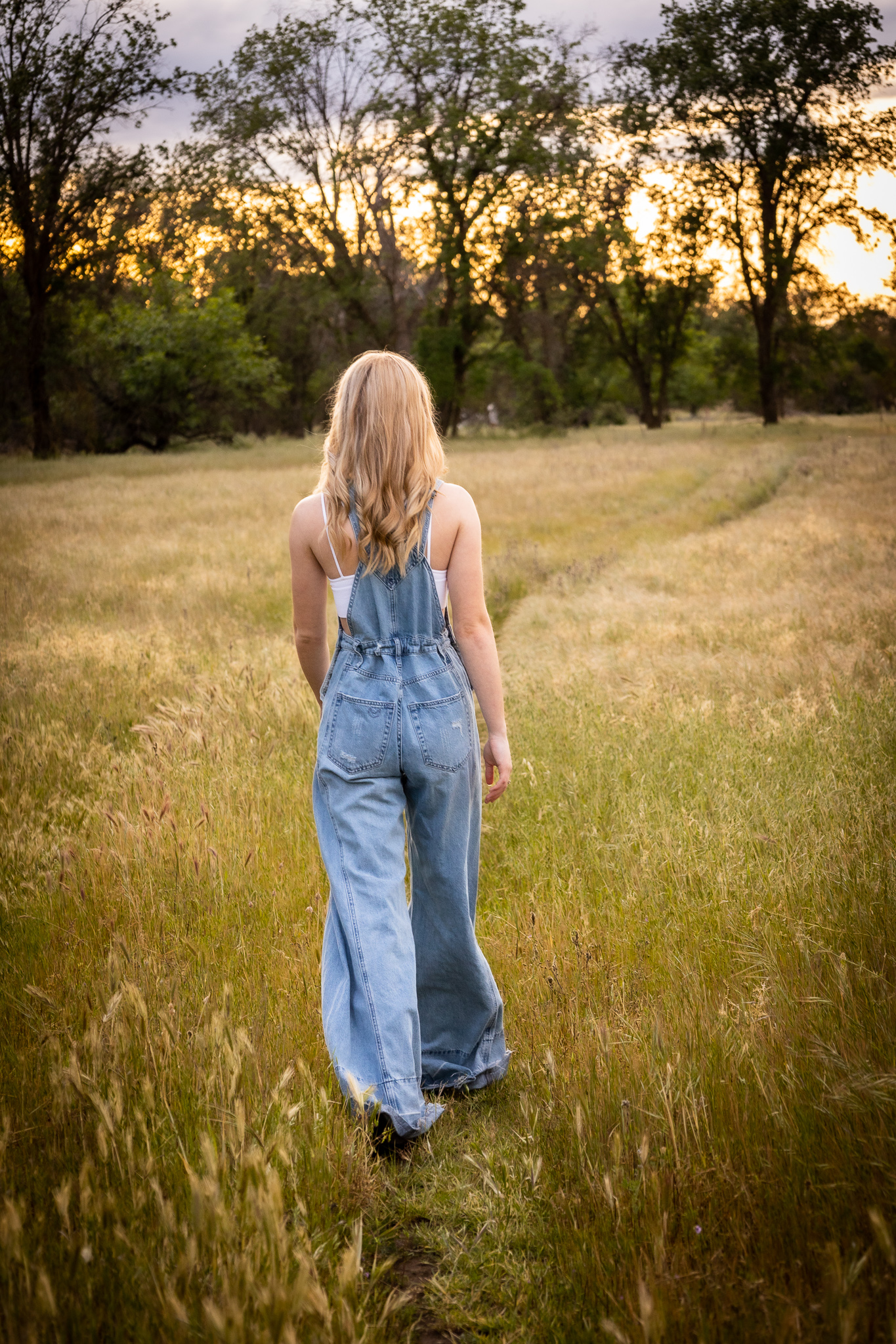 girl walking in tall grass during senior session in spring