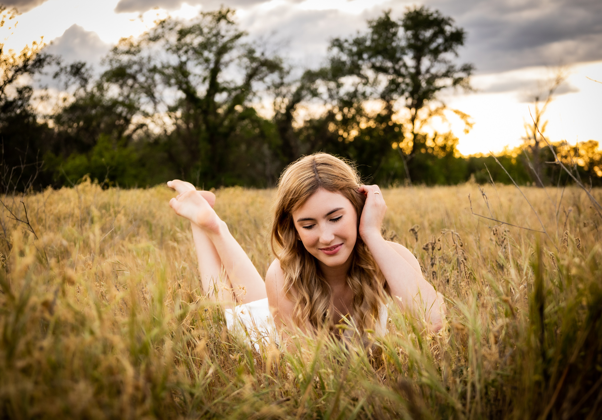 girl laying in field having senior photos taken