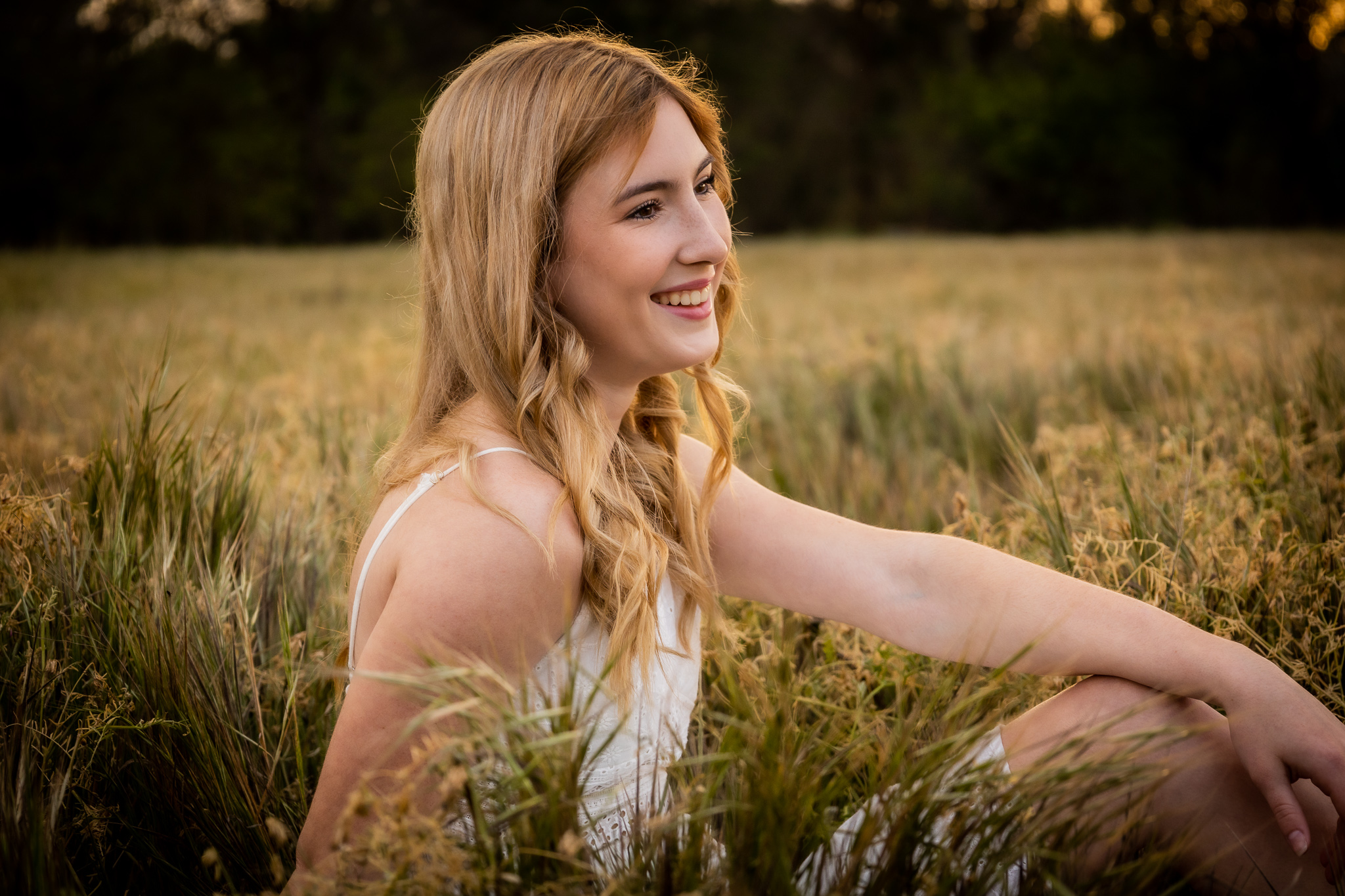 girl sitting in tall grass during senior session in red bluff ca