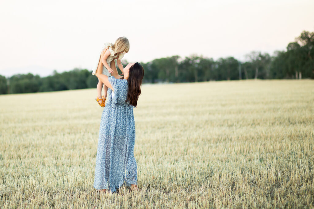 woman holding girl in field 