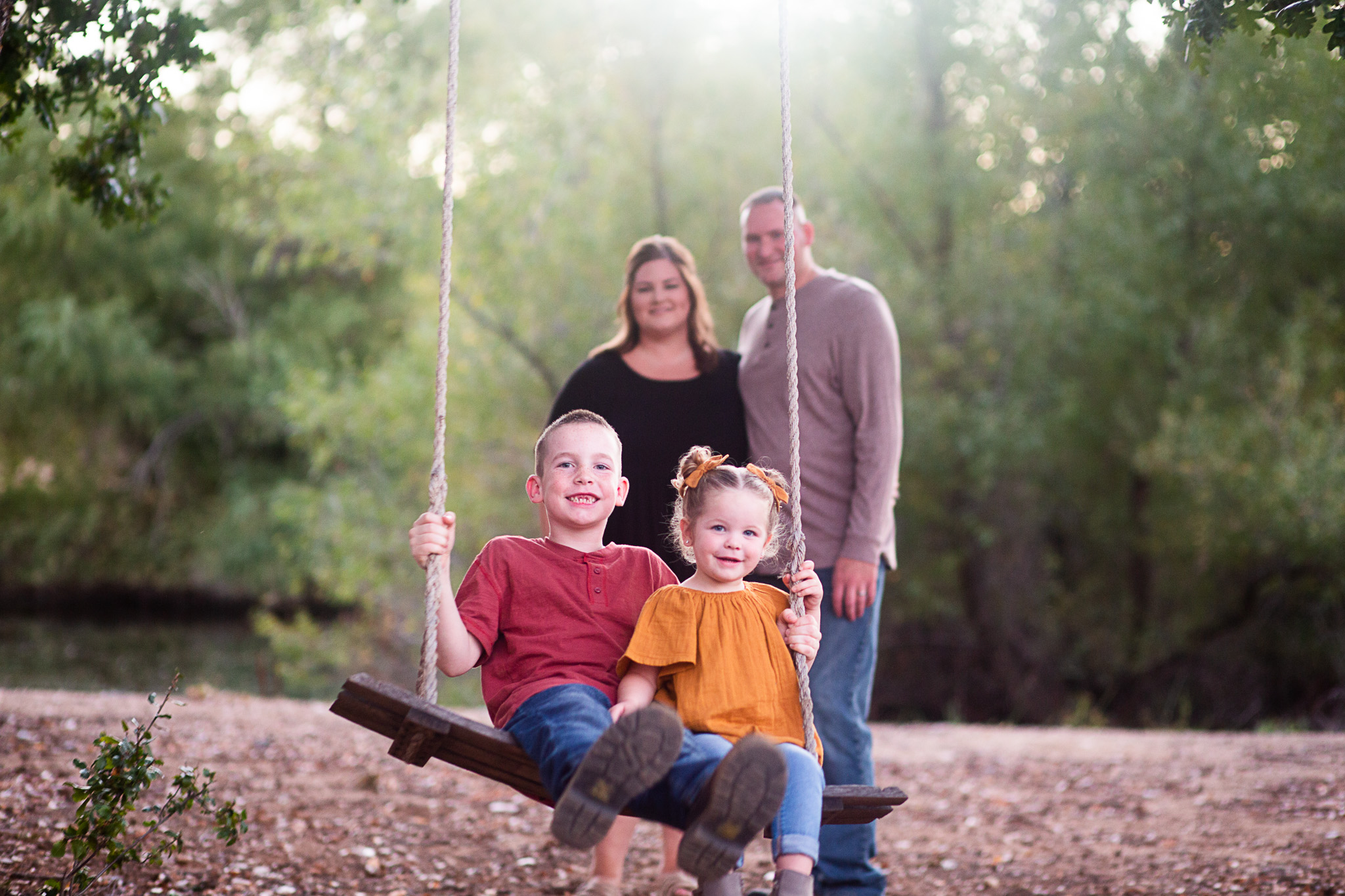 mom and dad pushing kids on swing