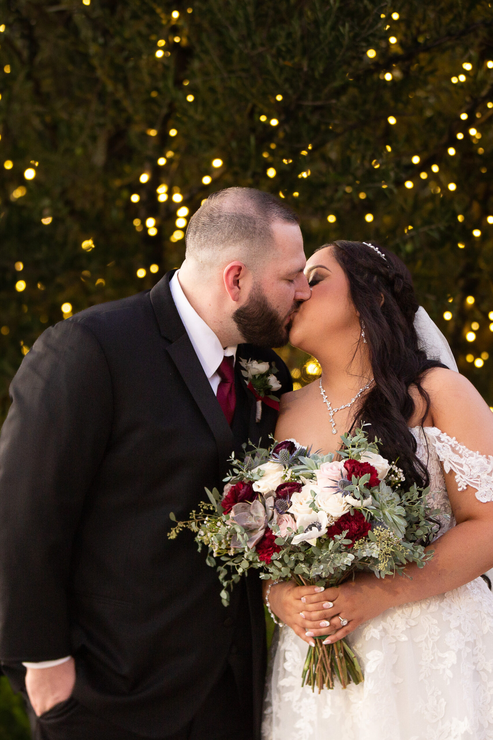 bride and groom in front of twinkle lights