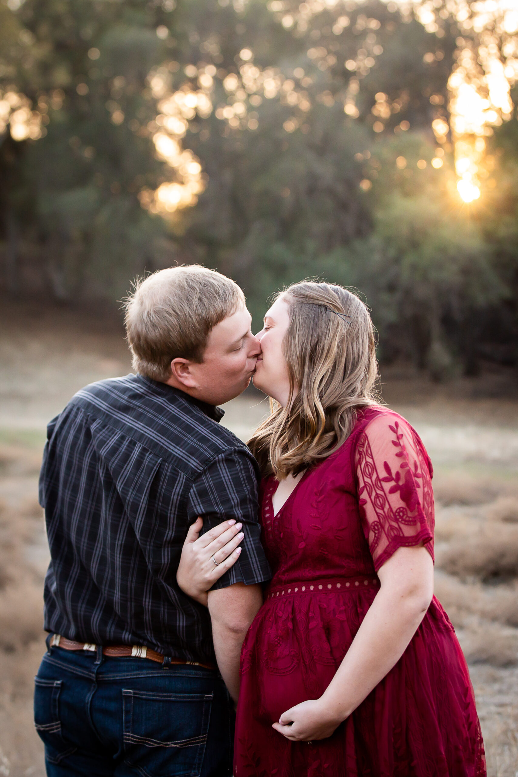 pregnant woman in red dress kissing husband