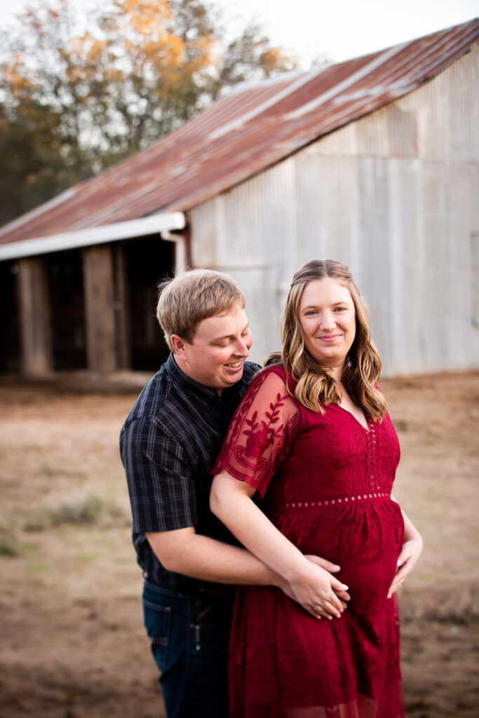 pregnant woman with husband in front of barn