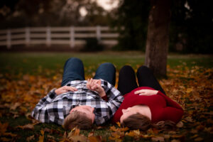 couple laying in the leaves during maternity session
