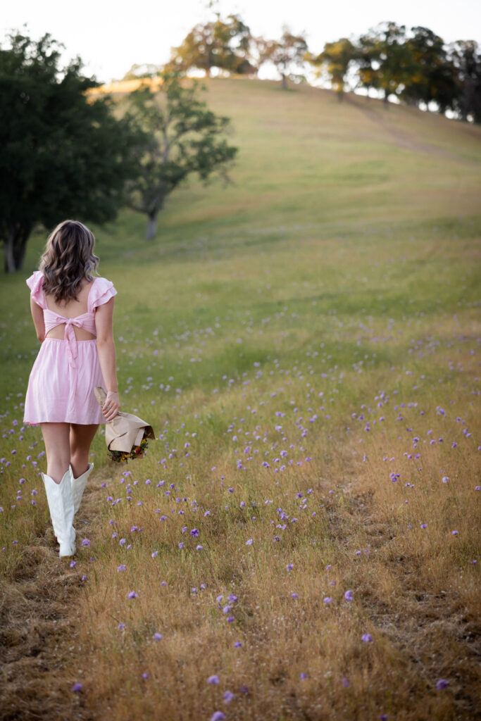 girl walking away holding flowers wearing pink dress