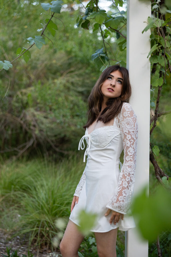 girl looking up standing next to grape arbor