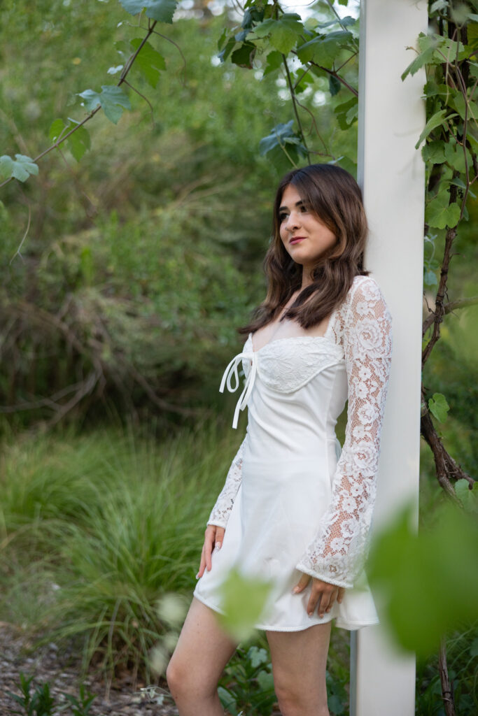girl leaning against grape arbor