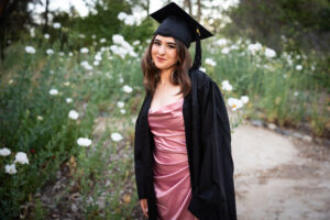 girl in cap and gown graduating in beautiful garden